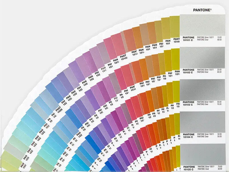 Fan-shaped Pantone color swatch book showcasing hues from green to red and grays