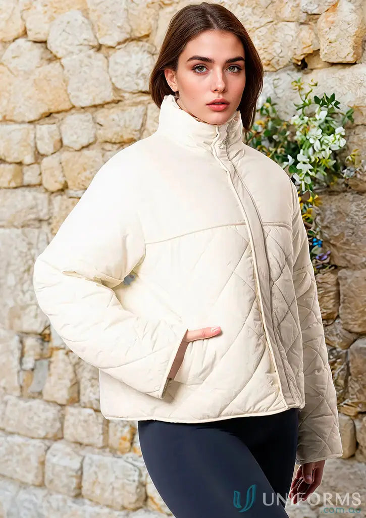 Cream quilted puffer jacket with high collar and long sleeves.