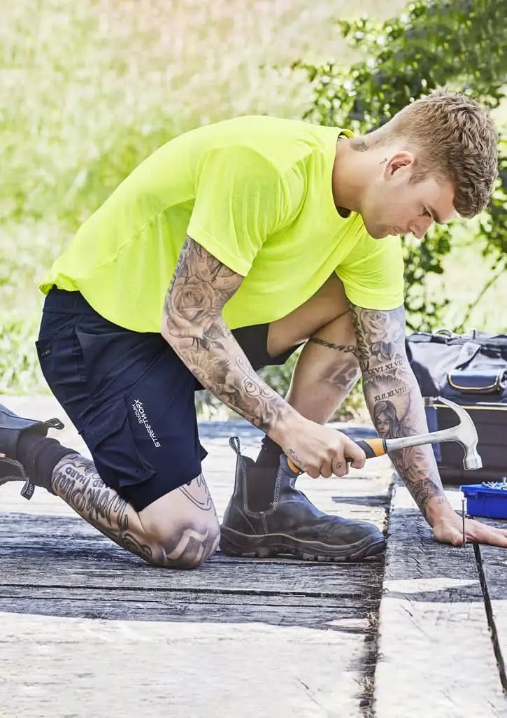 Man in work clothes hammering wearing Syzmik Men’s Streetworx Board Shorts