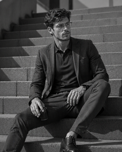 Man wearing dark glasses and a tailored blazer over a navy podium stretch polo perfect for work uniforms and workwear