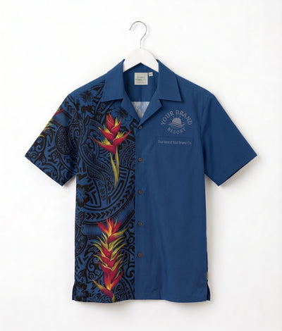 A short-sleeve button-up camp shirt hanging on a white hanger against a white wall. The shirt features a split design: one half is solid medium blue with a small white printed logo on the chest, and the other half has a black background with a colorful tropical floral and Polynesian pattern.