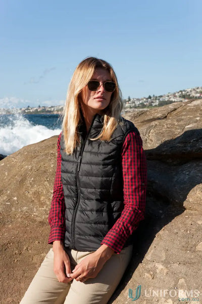 Ladies puffer vest with recycled polyester insulation over a red plaid shirt and khaki pants