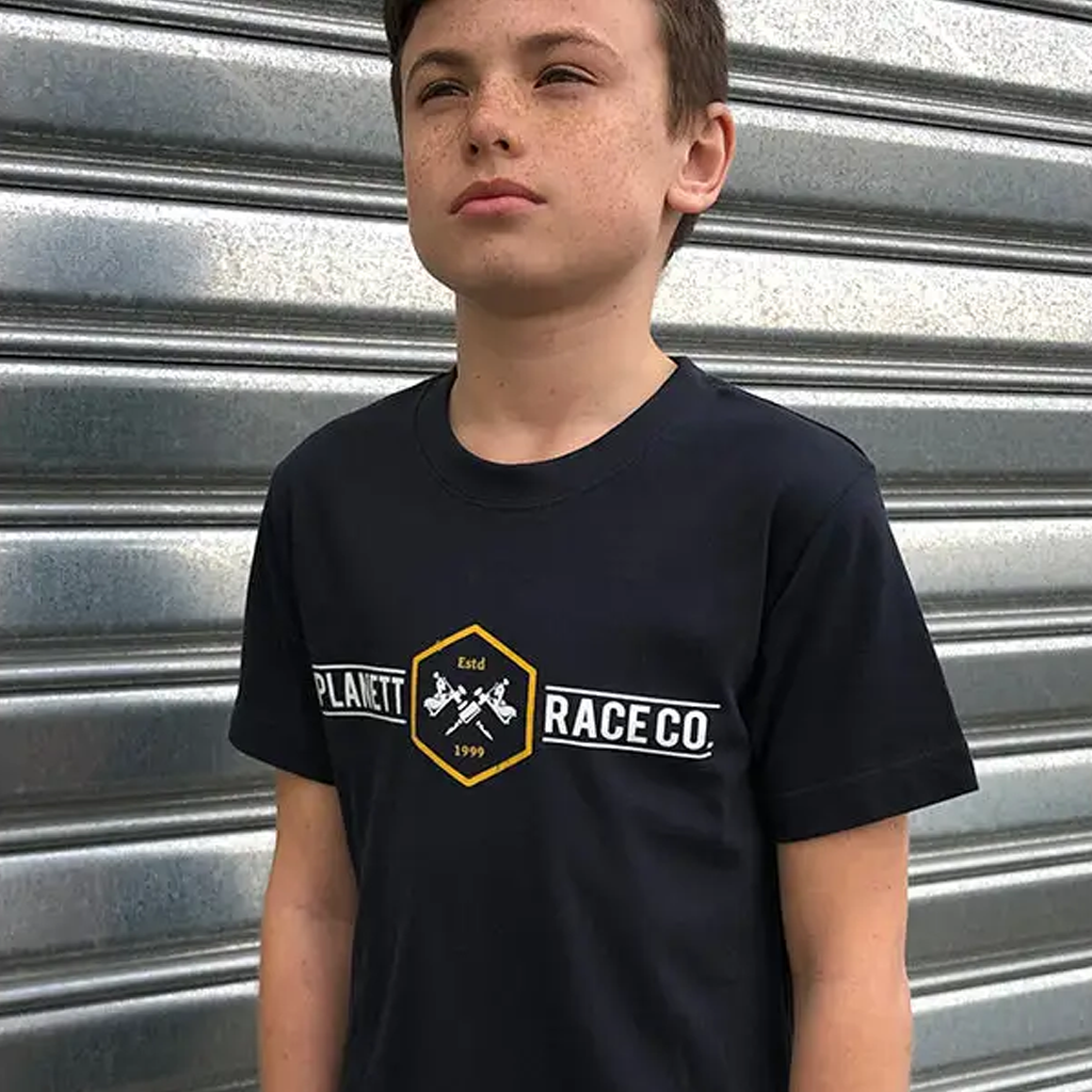 A boy wearing a navy blue t-shirt with a gold and white hexagonal logo.